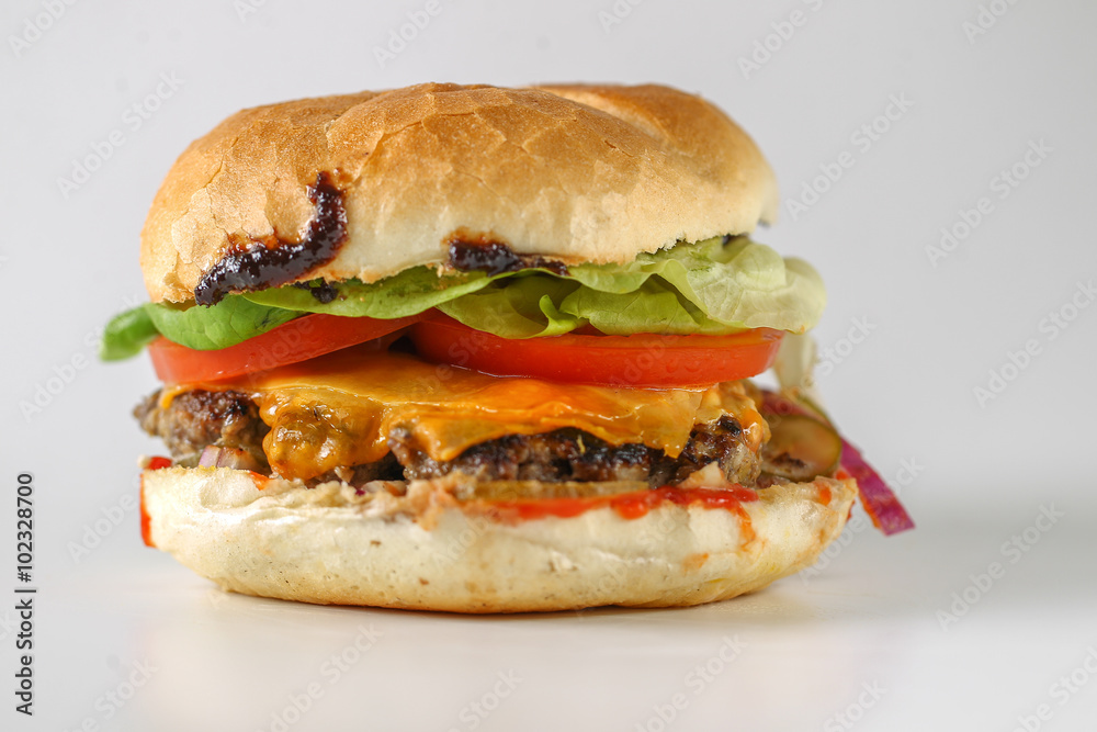 Tasty cheese beef burger with lettuce, cheddar, barbecue sauce, tomatoes, pickles and tzatziki Tasty cheese beef burger with lettuce, cheddar, barbecue sauce, tomatoes, pickles and tzatziki