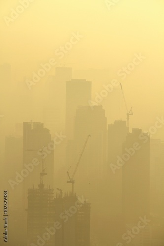 Buildings under construction with cranes in misty sunrise, Bangkok, Thailand