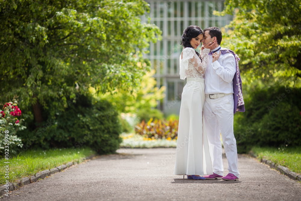 Romantic fairytale married couple in white clothes kissing in ga Romantic fairytale married couple in white clothes kissing in ga