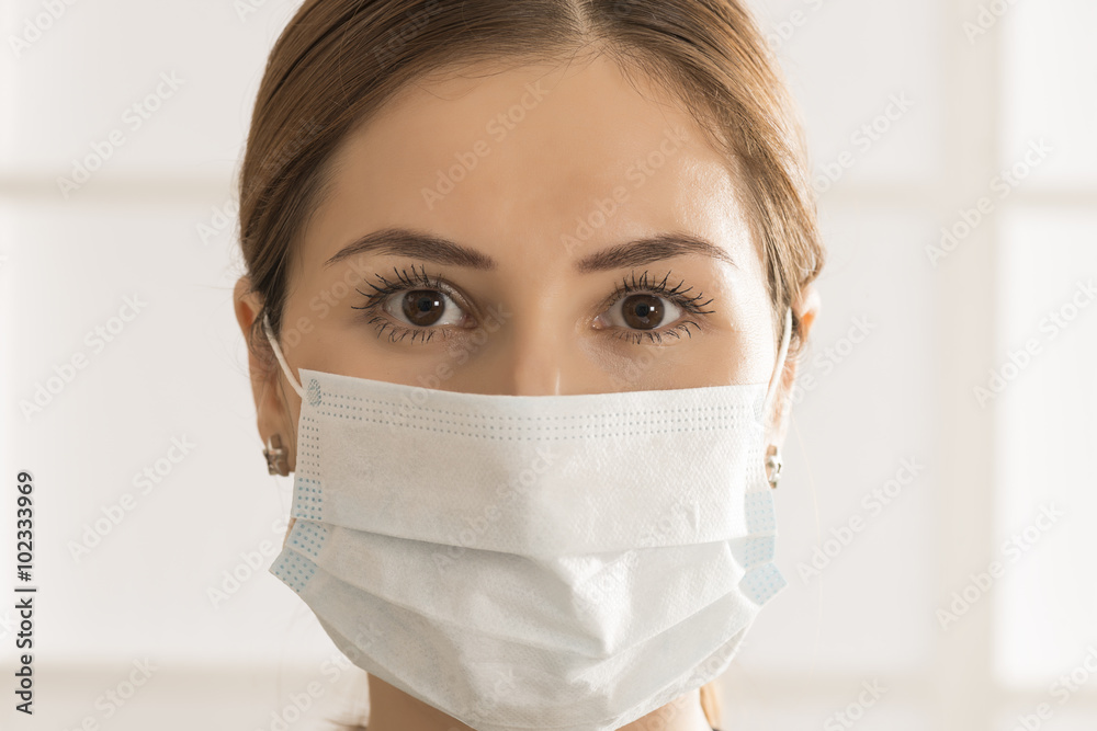 Close up portrait of young woman with medicine healthcare mask against white room background Close up portrait of young woman with medicine healthcare mask against white room background