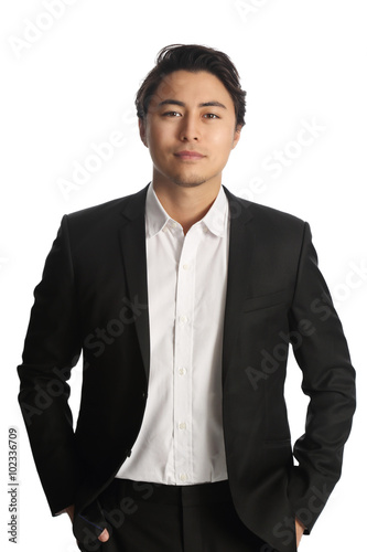 An attractive businessman wearing a black blazer with a white shirt, standing against a white background looking at camera. Smile on his face. 