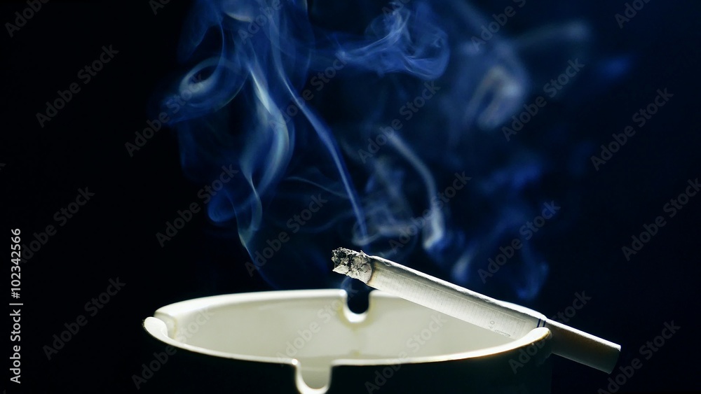 Smoldering cigarette in the ashtray with ash, nicotinic blue smoke. Smoking tobacco Smoldering cigarette in the ashtray with ash, nicotinic blue smoke. Smoking tobacco