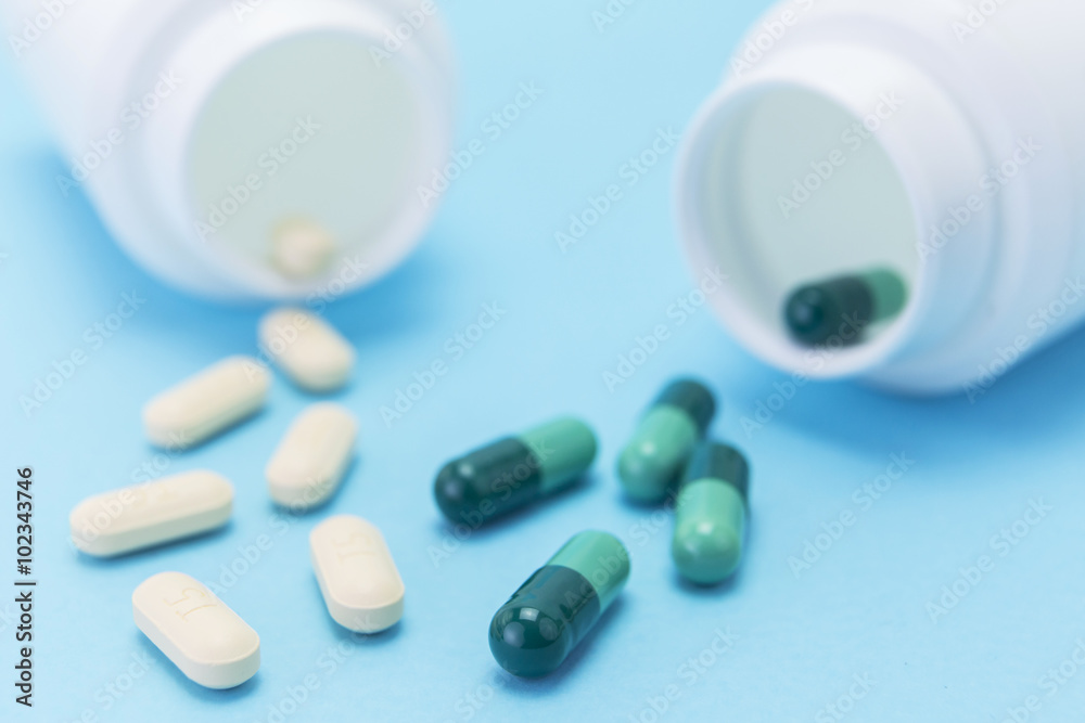 white pills out of the bottle on blue background white pills out of the bottle on blue background