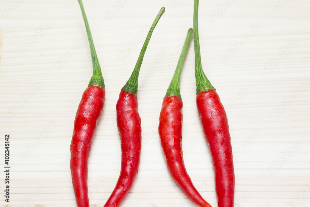 the red chili on the light brown wooden background