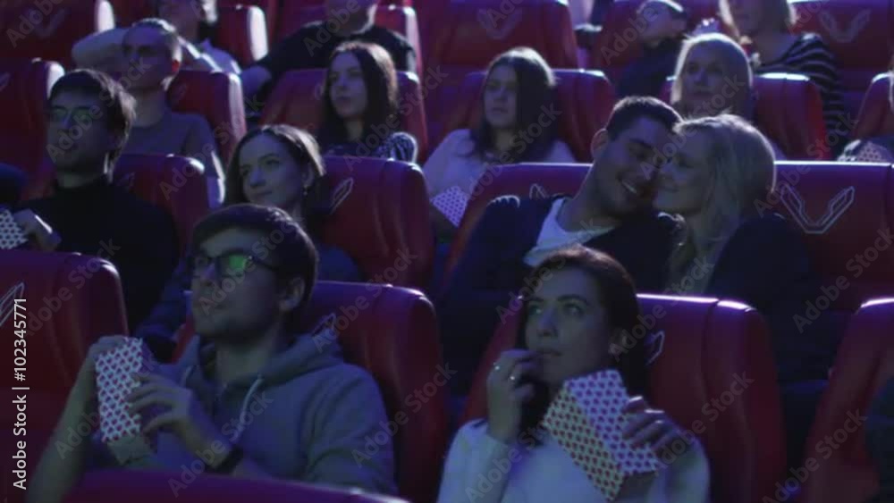 Young romantic couple is making out and kissing while watching a film screening in a movie cinema theater. Shop on RED Cinema Camera.