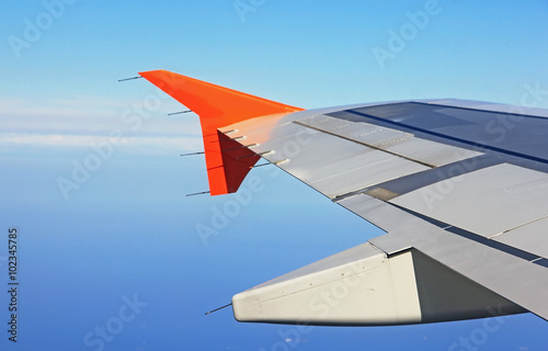 Aircraft wing in flight, view from the window at the blue sky ai