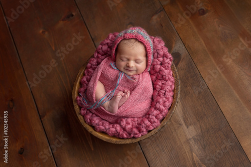 Newborn Girl Sleeping in Wooden Bowl photo