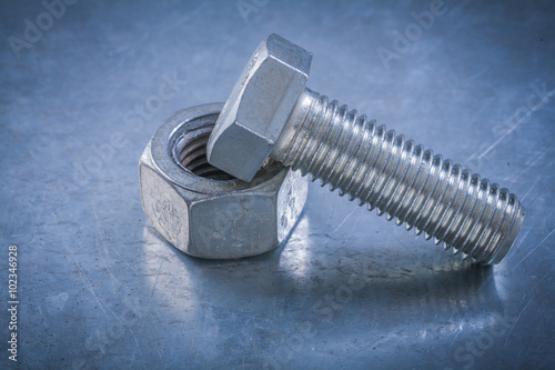 Metal bolt on screw-nut metallic background maintenance concept
