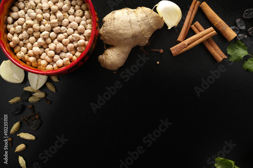 Chickpea and indian spices fresh and dried on black background, photo