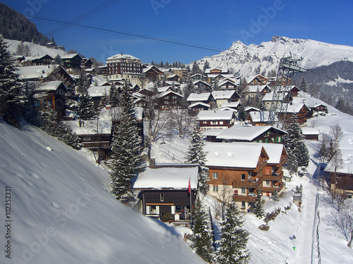 Quaint snowy village of wooden homes on Swiss mountain - landscape photo photo