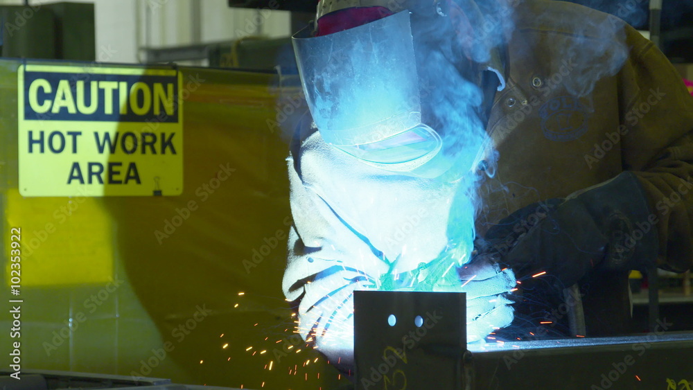 Sparks fly as a welder welds steel, with 