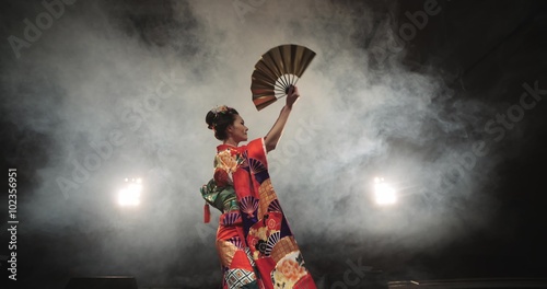 4K beautiful Japanese geisha dancing on stage and posing for the camera,the smoke in the background, slow motion