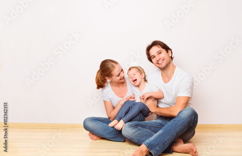 Happy family on  floor near  empty  wall in the apartment bought © JenkoAtaman