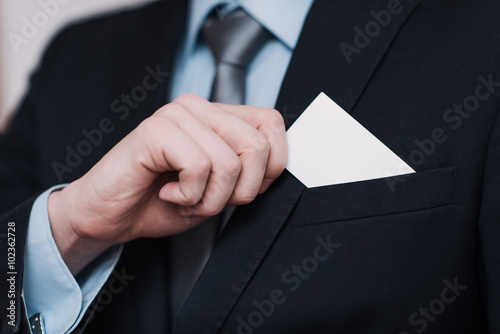 businessman in a black suit and gray tie place or take out credit card in pocket