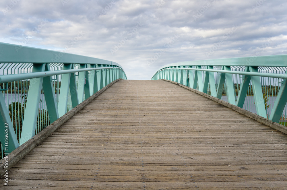 Wooden Footbridge with Metal Railings on a Cloudy Day