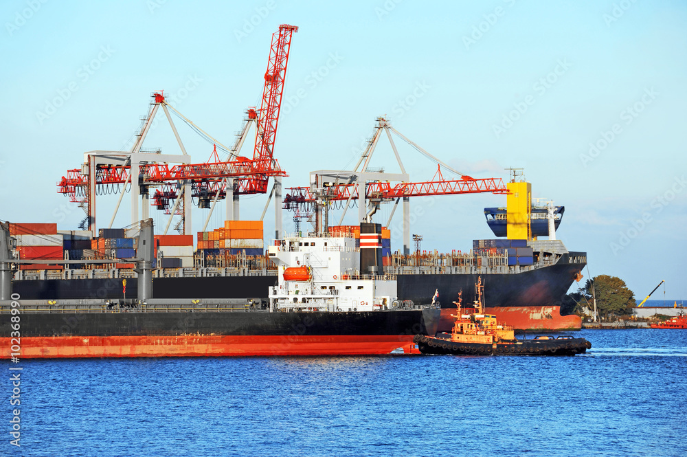 Tugboat assisting container cargo ship
