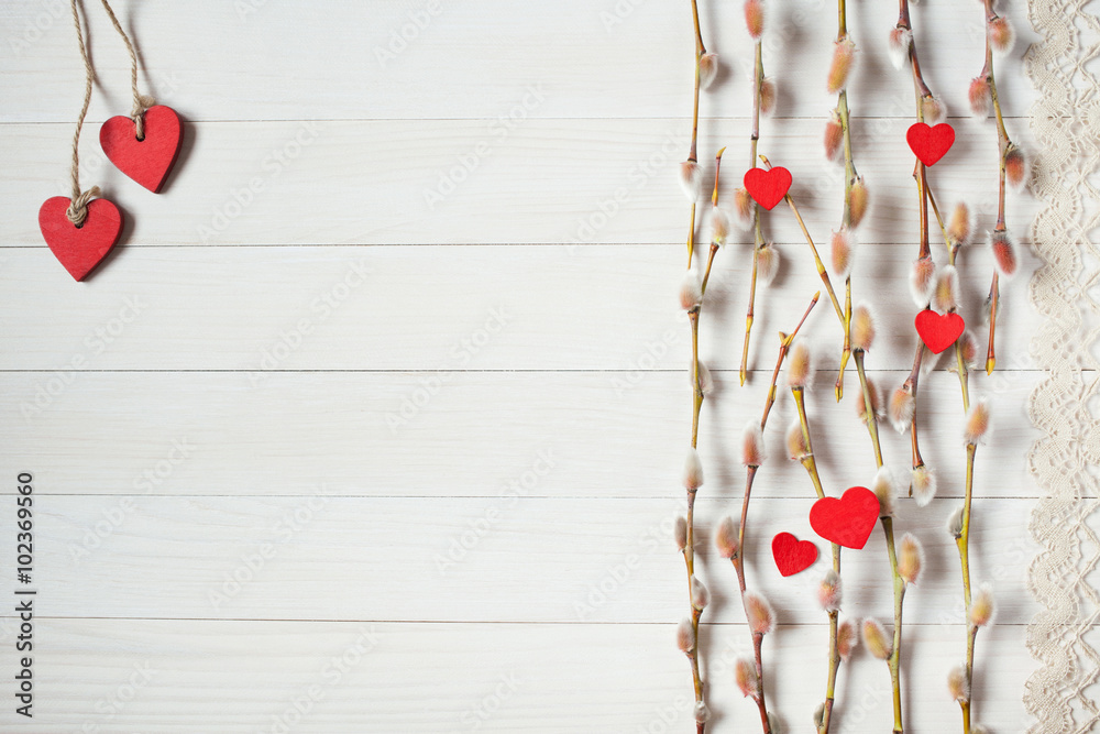Light wood background with willow branches and red hearts Light wood background with willow branches and red hearts