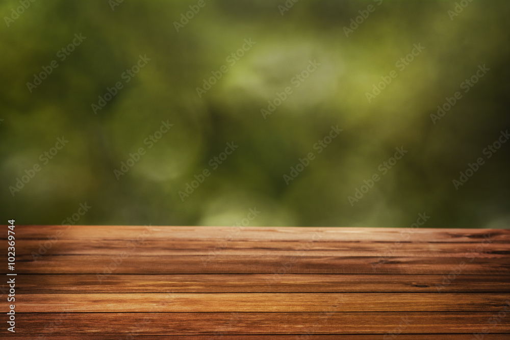 Natural bokeh background with wooden table surface and green copy space in the distance. Copy space for concept or advertising. Natural bokeh background with wooden table surface and green copy space in the distance. Copy space for concept or advertising.