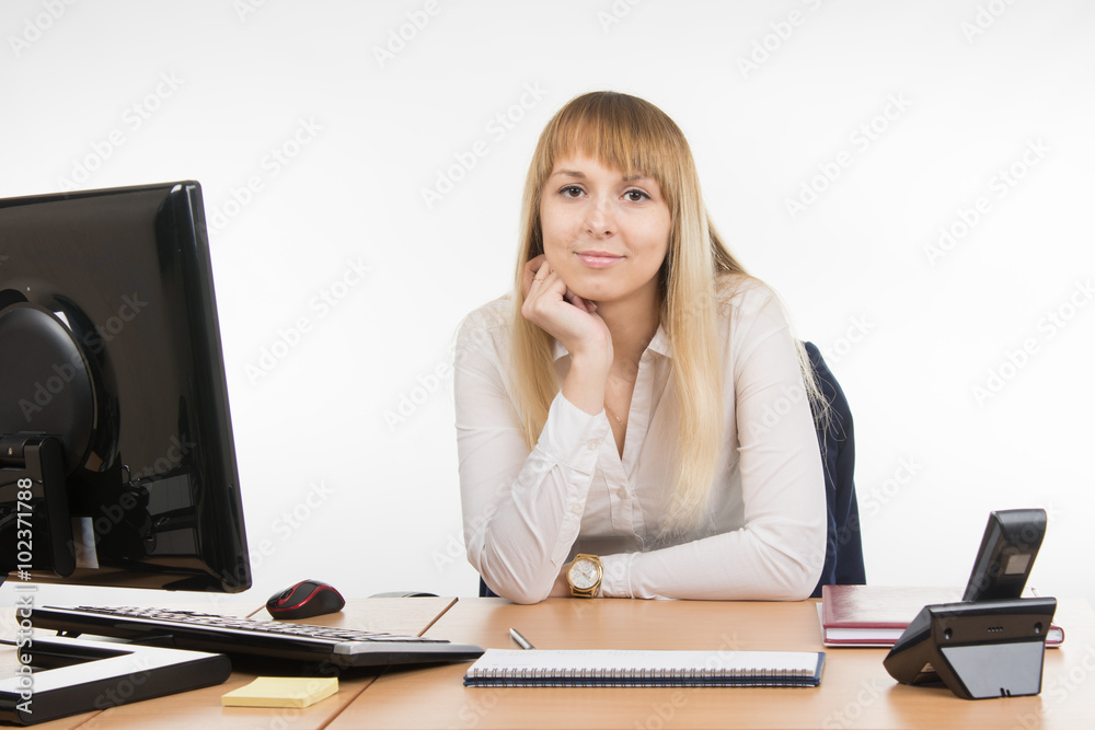 Business woman sitting at a desk in the office and looking at the frame Business woman sitting at a desk in the office and looking at the frame