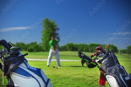 Fototapeta Naklejka Na Ścianę i Meble -  Two cart bags and a golfer on a golf course ready to swing