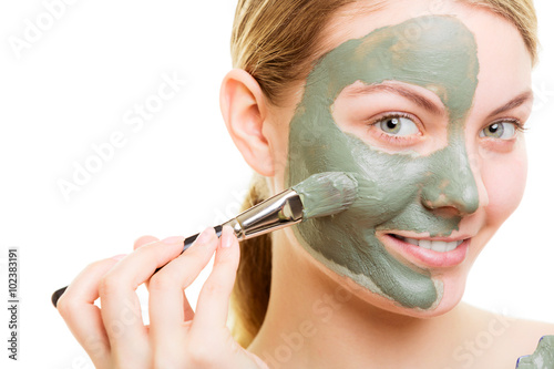 Woman applying with brush clay mud mask her face