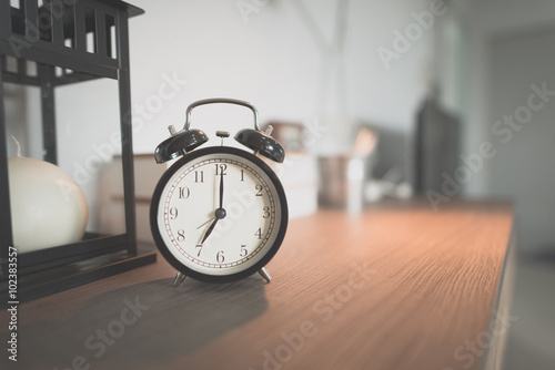 Toned Photo alarm clock showing 7 o'clock on table in bedroom (Vintage,noise and Grain)
