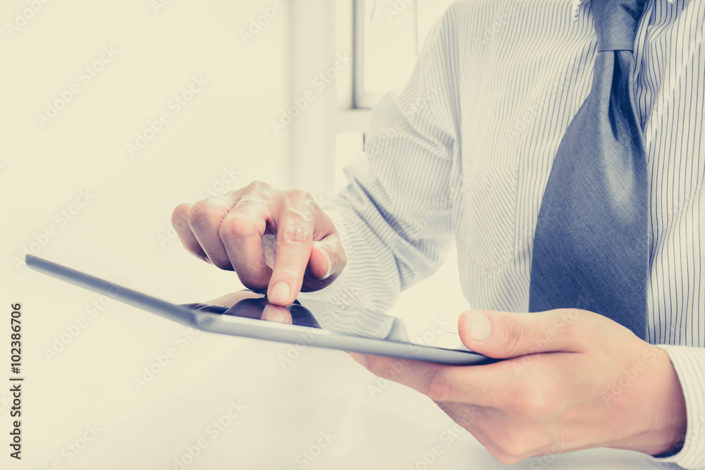 Businessman using tablet computer with one hand touching the screen Businessman using tablet computer with one hand touching the screen
