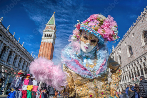 Carnival mask against bell tower on San Marco square in Venice