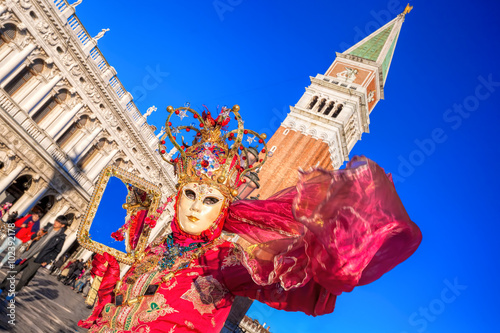 Carnival mask against bell tower on San Marco square in Venice