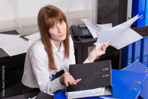 Overworked businesswoman with folders.
