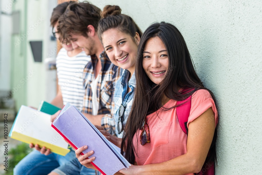 Hip friends leaning against wall and reading notebooks Hip friends leaning against wall and reading notebooks