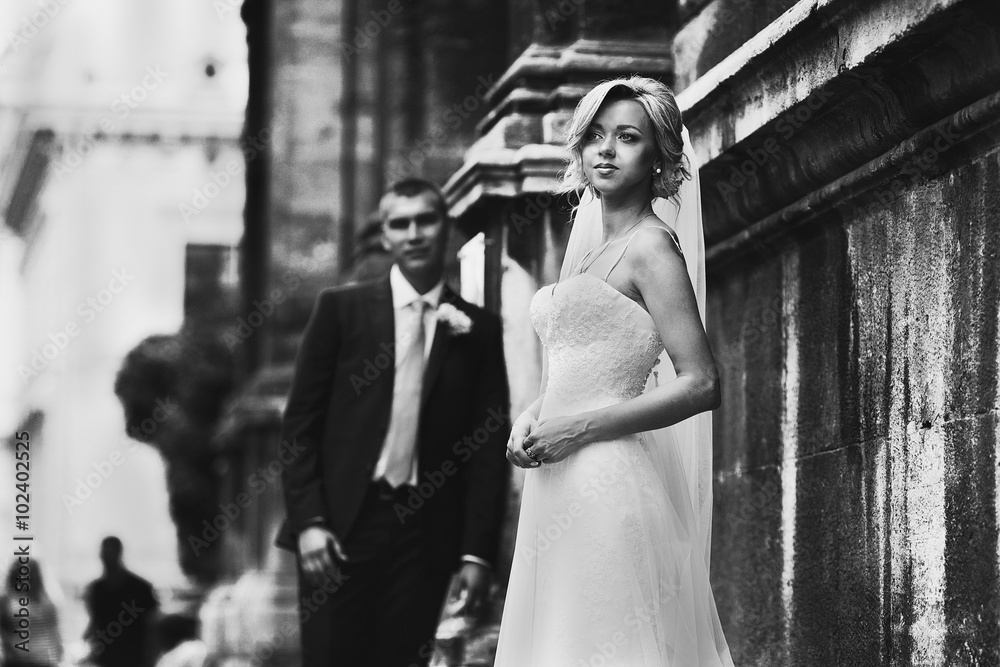 Obraz premium Bride and groom posing near old baroque church b&w