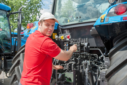 Young repairman ( farmer )  repairs tractor