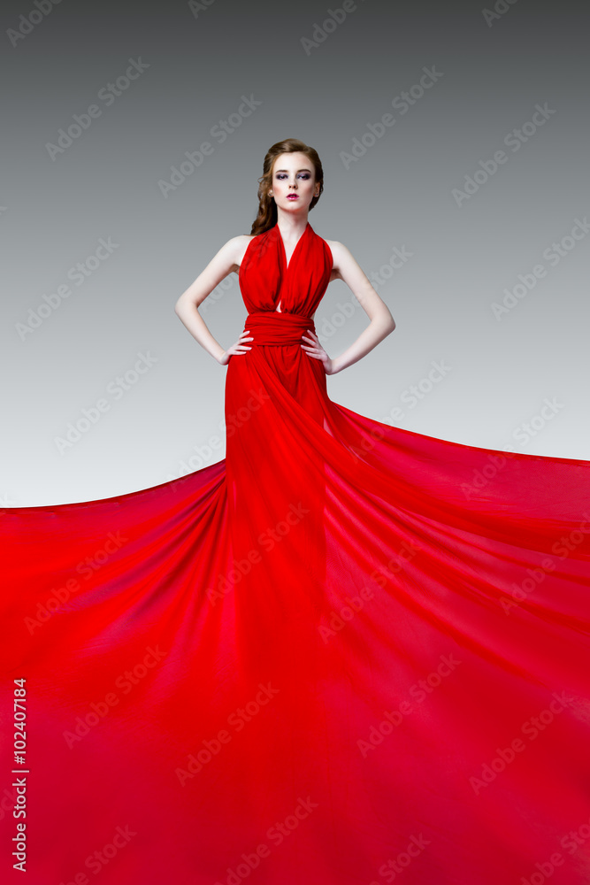 Fashion photo of young magnificent woman in red long dress, studio photo