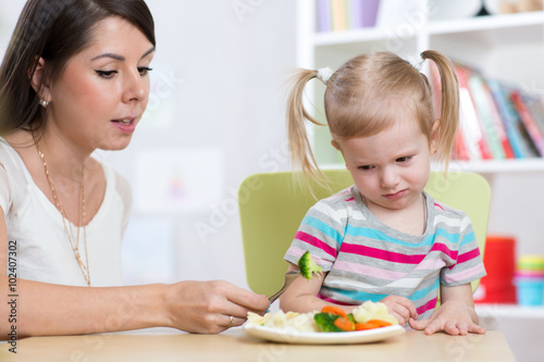 Cuadro en lienzo Child girl looks with disgust at healthy vegetables
