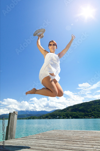 Junge Frau relaxt im Sommer am See auf dem Bootssteg