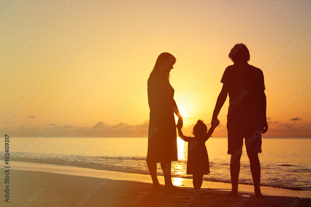 Happy family with little daughter together at sunset