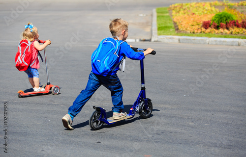 two kids boy and girl riding scooters