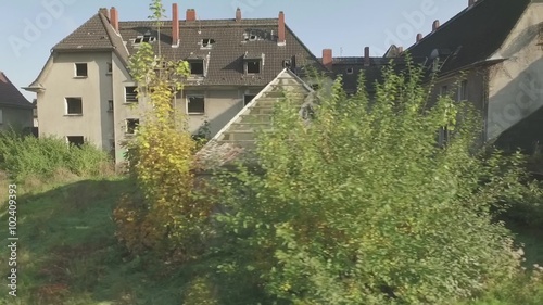 Wallpaper Mural Aerial of an abandoned quarter in the coal-mining town Gladbeck, Germany, low altitude flight, close tracking shot from left to right in front of a shabby row of houses and coppice. flat s-log. Torontodigital.ca