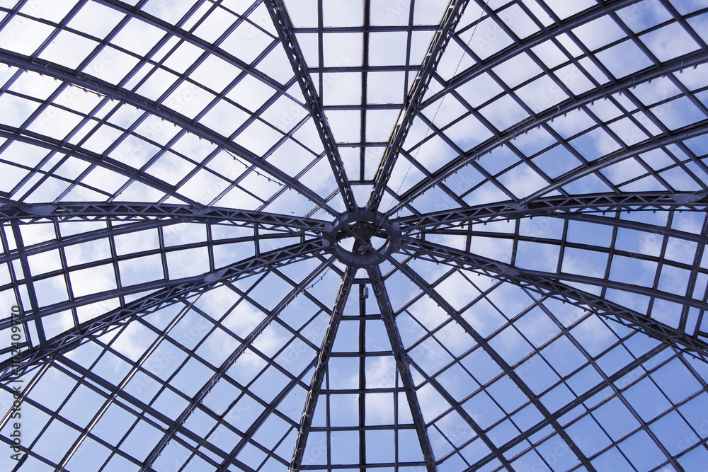 Glass roof of a building against the background of blue sky (view from the inside)