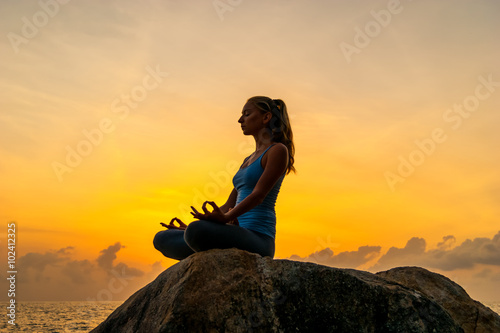 Woman sitting on a rock near sea and meditate at dawn on a tropical island Koh Samui  Thailand