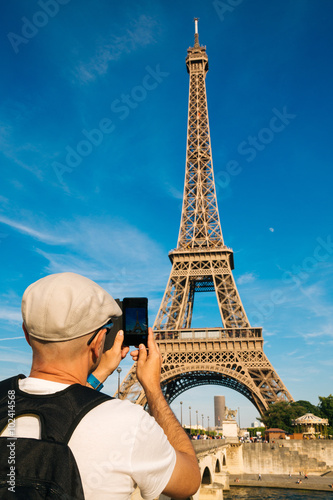 Tourist man taking pictures of the Eiffel Tower with a smart phone © asife