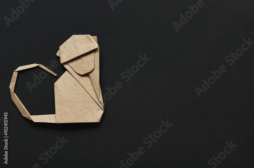 Folded paper origami moncey on black background. Postcard template. photo