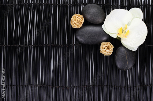 Orchid with zen stones and wicker balls on black background