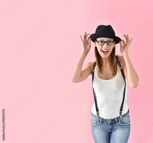 Fashion girl with hat and eyeglasses, isolated on pink background © goodluz