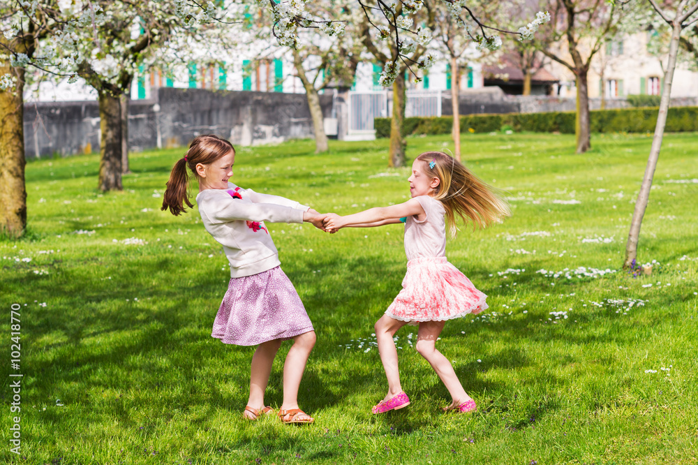 Two little girls playing in spring garden on a nice sunny warm day, wearing skirts Two little girls playing in spring garden on a nice sunny warm day, wearing skirts