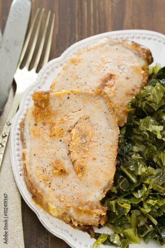pork with cabbage on white plate on brown wooden background