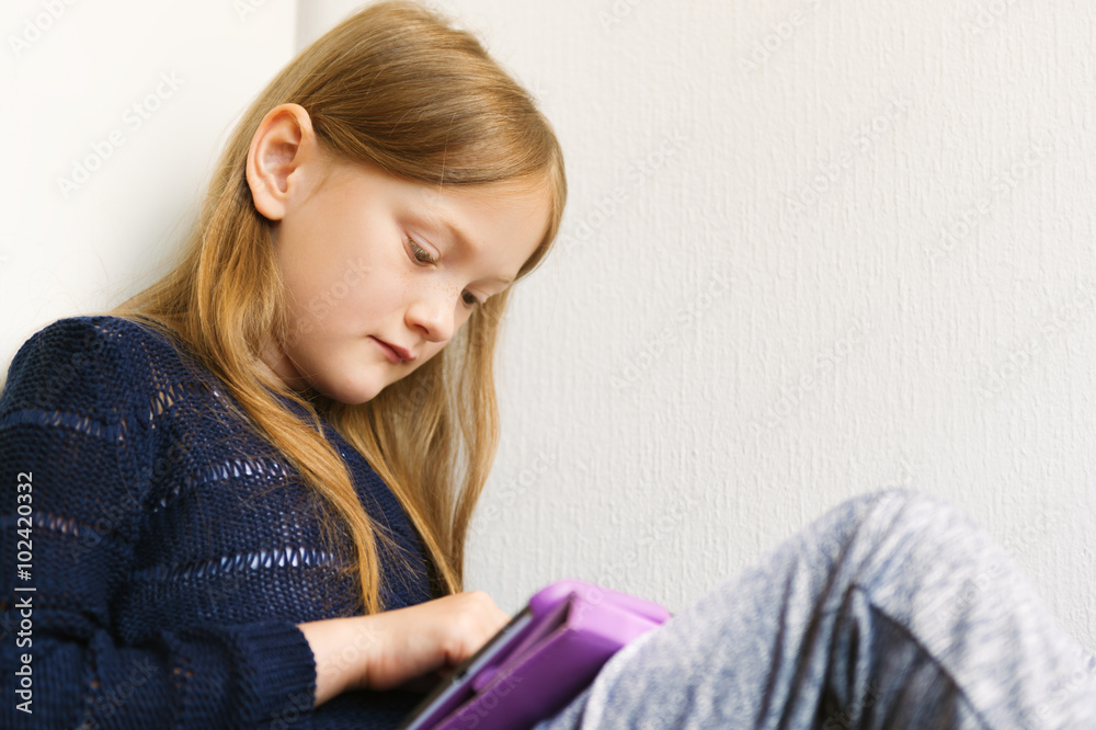 Adorable little girl playing on a digital tablet Adorable little girl playing on a digital tablet