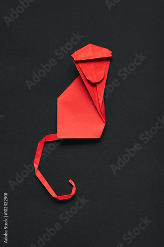 Folded paper origami moncey on red eco background. Vertical postcard template. photo