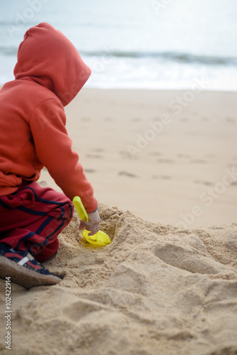 Kid playing on the beach with sand shovel